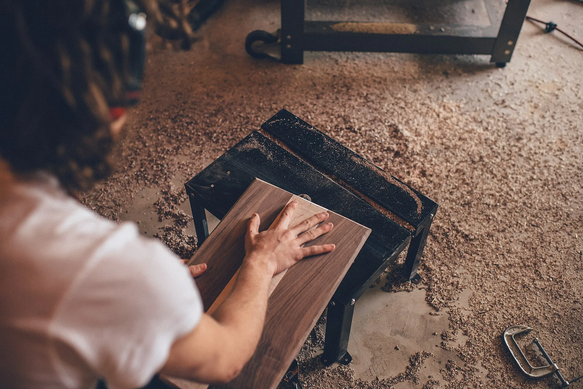 Woodworker sanding a wooden board by hand in the workshop